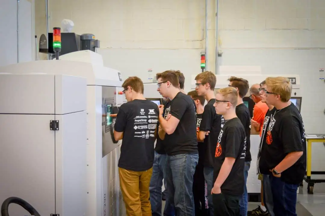 Students observing a DMLS 3D printer while on a tour at Baker Industries for Manufacturing Day 2016